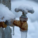 Outdoor water spigot covered in ice and snow
