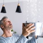 Man holding bucket to catch leaking water