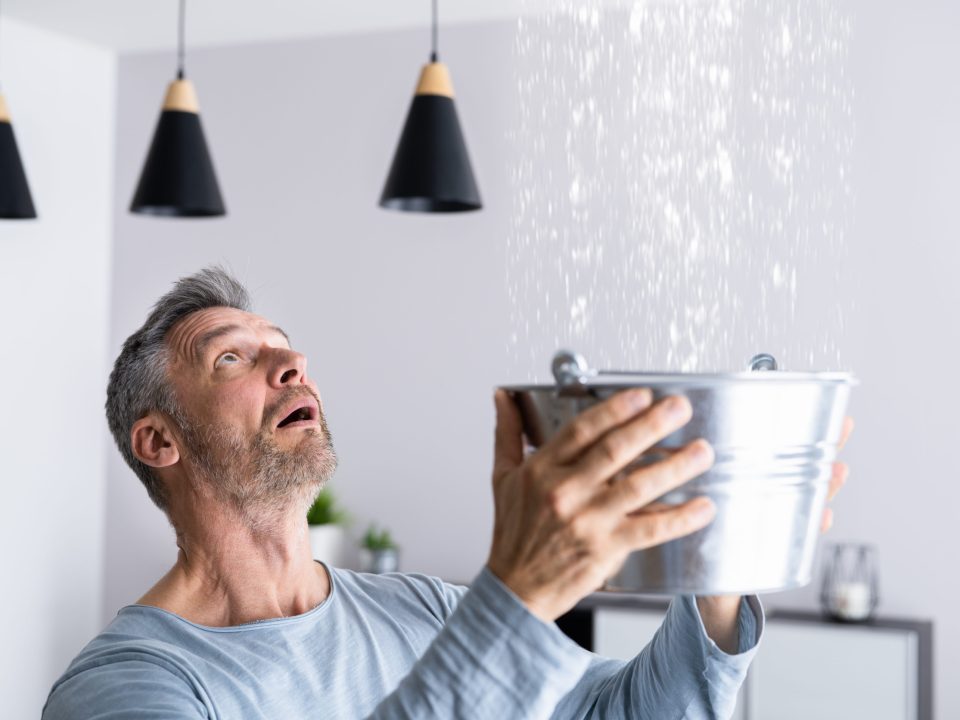 Man holding bucket to catch leaking water
